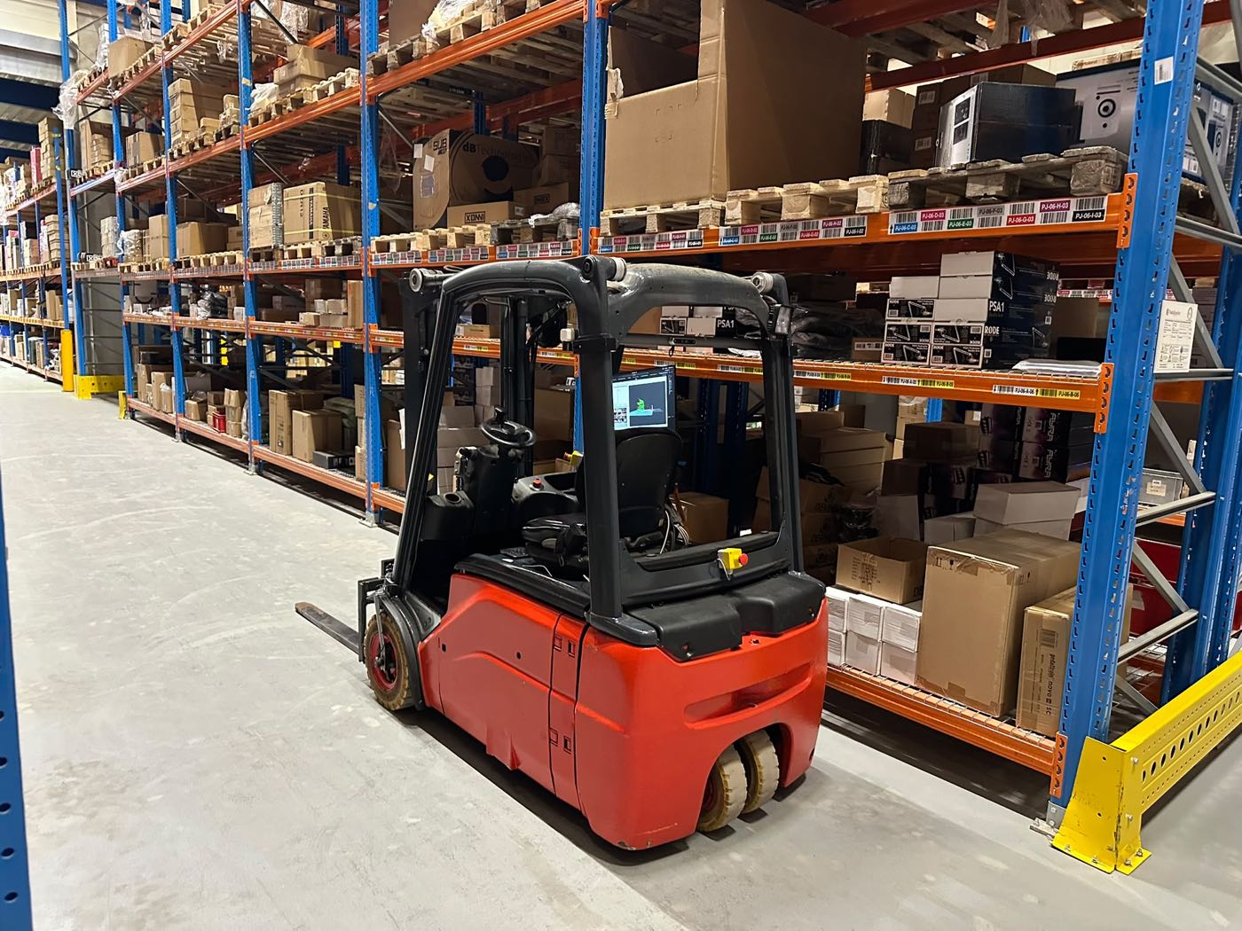 Autonome heftruck in een magazijngang tussen de stellingen